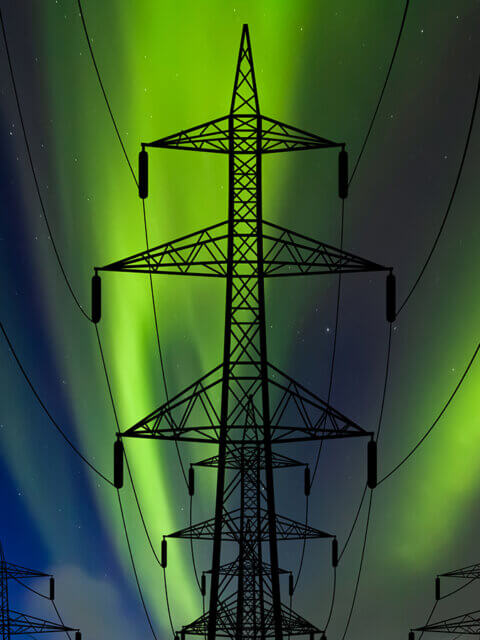 High voltage towers against the backdrop of the Northern Lights